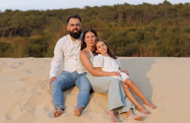 A family enjoying a peaceful moment on sandy dunes in Ponte de Lima, Portugal.