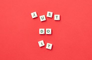 Motivational phrase 'Just Do It' spelled with Scrabble letters on a red background.